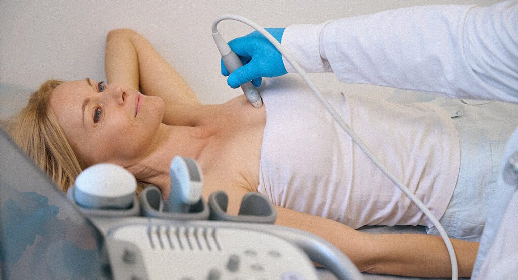Middle-aged woman at an ultrasound appointment having her breast examined by doctor.