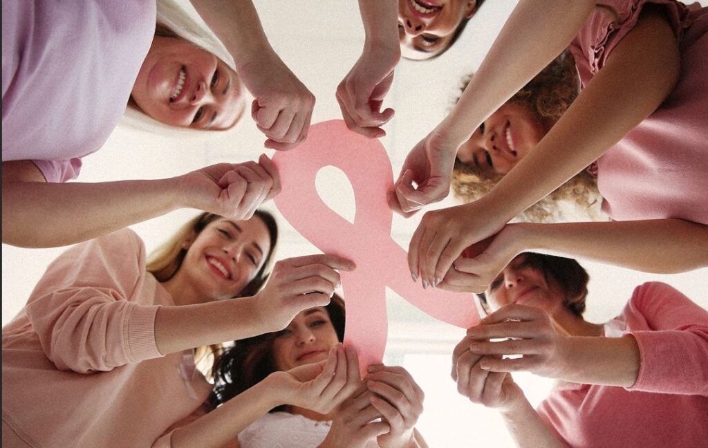  Vue de dessous de femmes tenant un ruban de cancer du sein en papier rose comme concept de sensibilisation au cancer du sein.