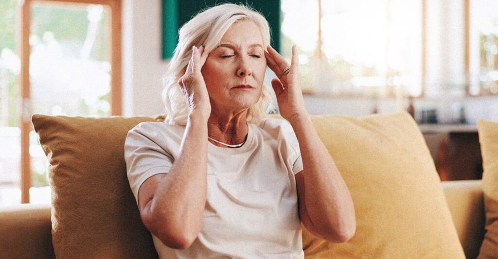 Femme âgée, les yeux fermés, se tenant les tempes, souffrant d'un mal de tête de tension due à un niveau de stress élevé.