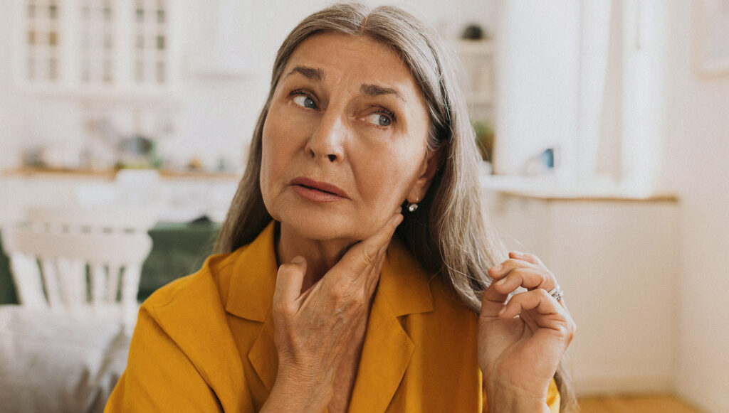 Femme âgée ressentant une douleur au cou, thyroïde enflée.