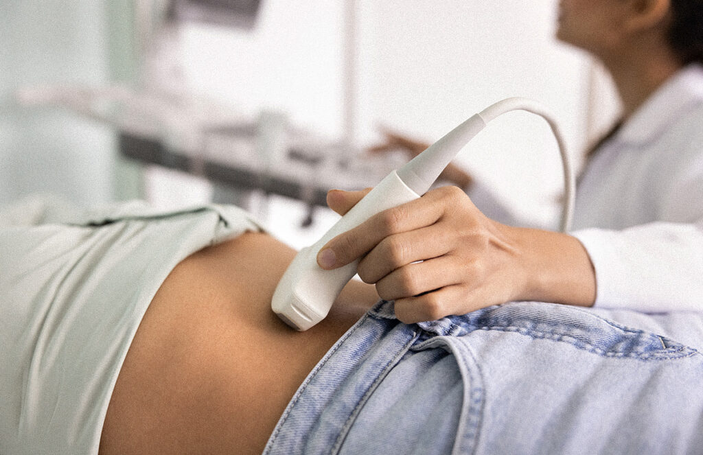Gros plan sur une femme médecin utilisant un échographe sur l'abdomen d'une patiente