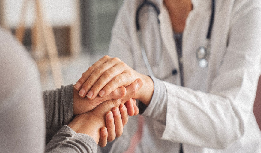 Gros plan sur un médecin tenant les mains d'un patient avec compassion et bienveillance.