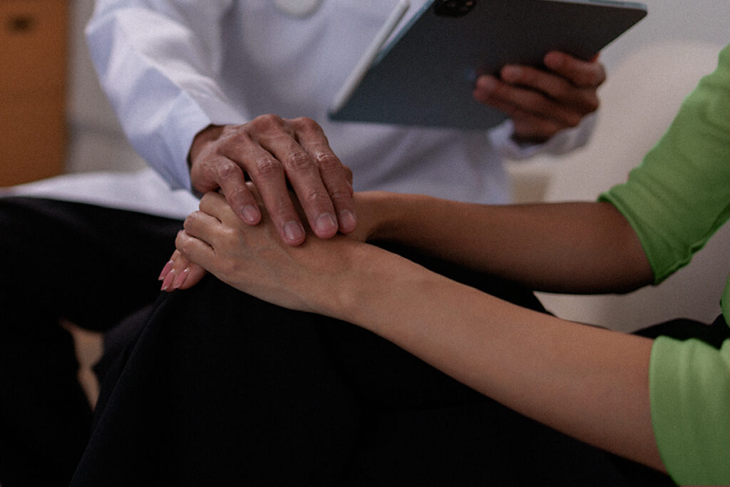 Healthcare provider offering comfort by holding a patient's hand during an appointment.