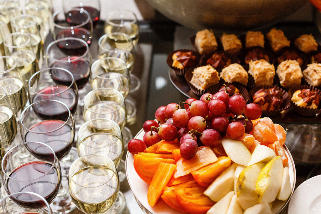 Verres de vin rouge et blanc à côté d’un assortiment de fruits frais et de desserts des Fêtes.