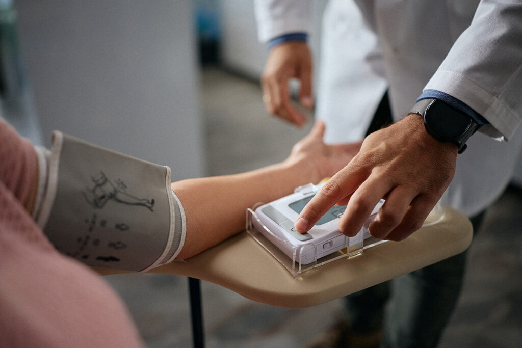 Un médecin mesure la tension artérielle d'un patient à l'aide d'un tensiomètre électronique et d'un brassard.
