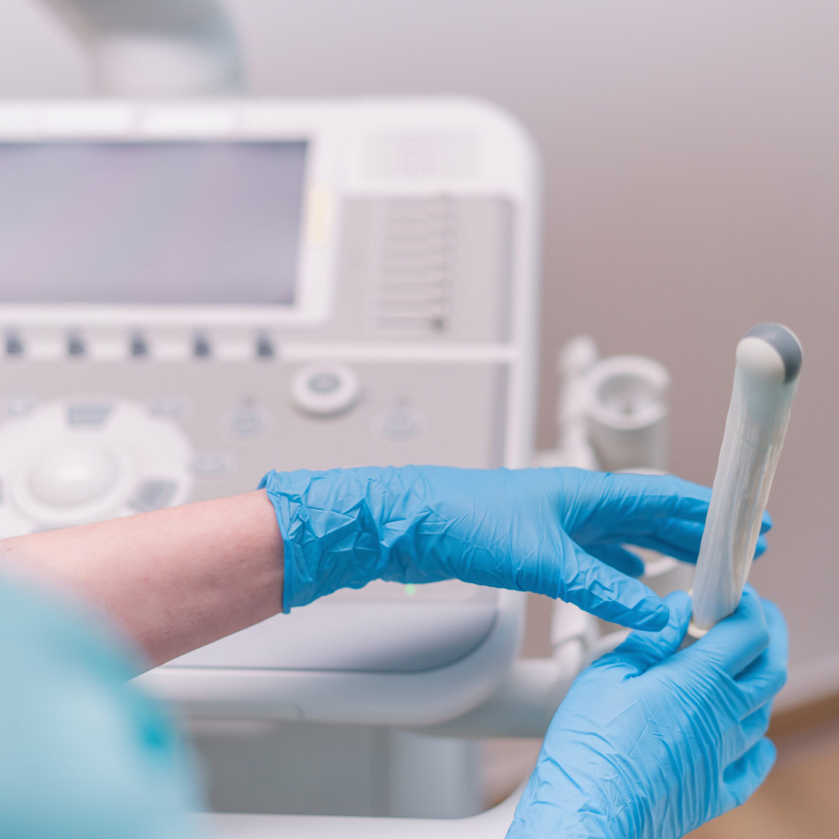 A gynecologist holds a transvaginal ultrasound device in his hands for diagnosing a patient in the clinic