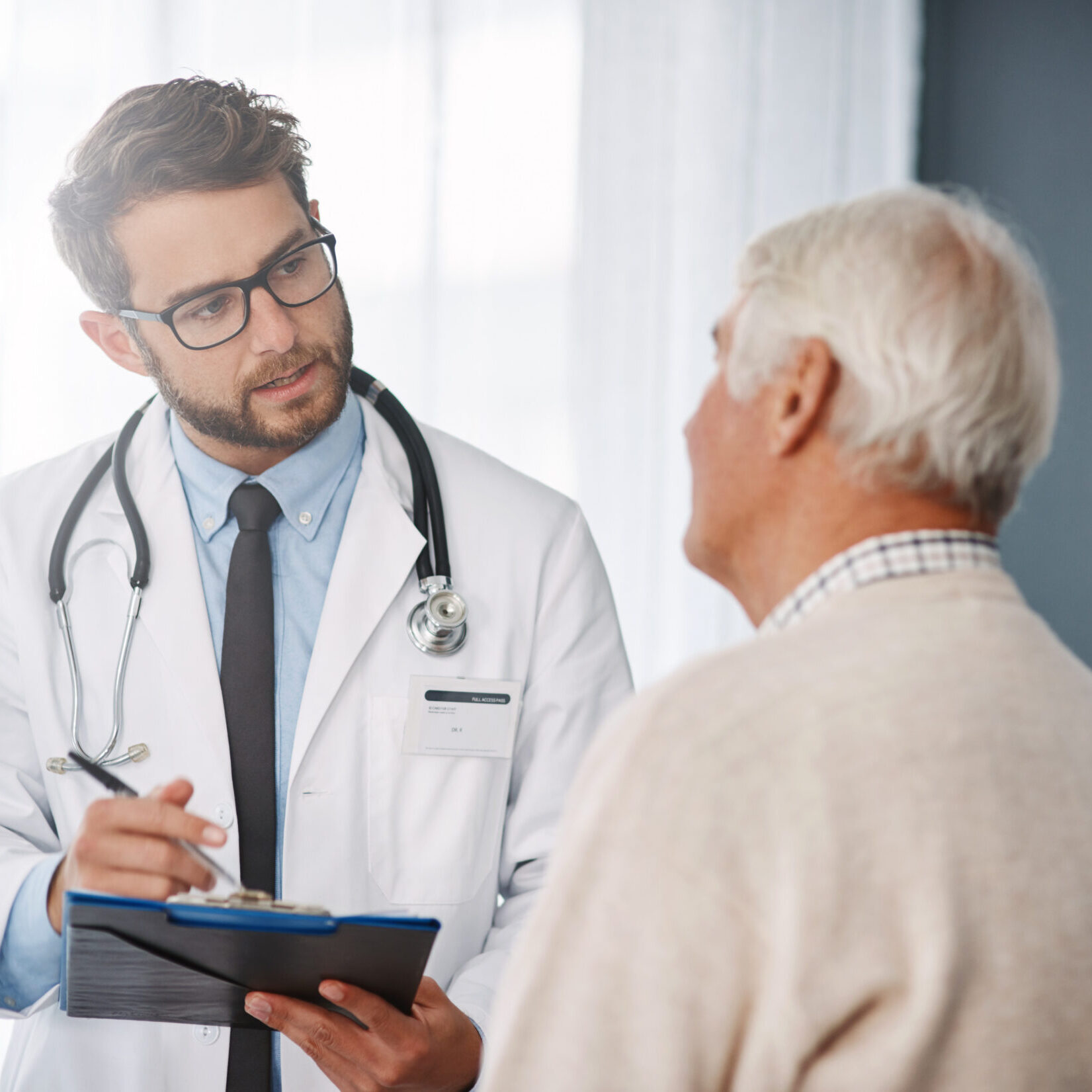 Cropped shot of a young male doctor going through medical records with his senior male patient.
