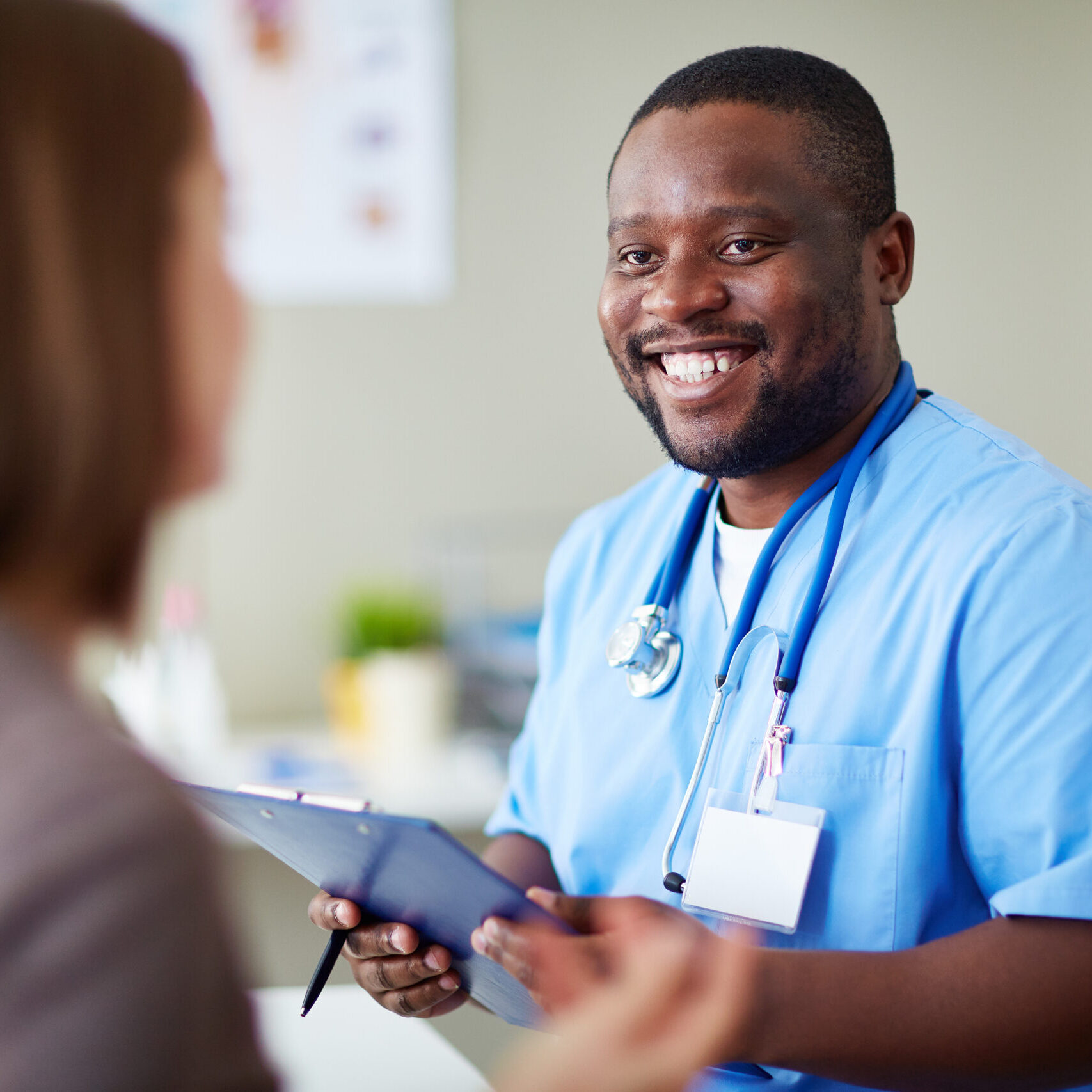 Smiling African doctor working with patient in his office